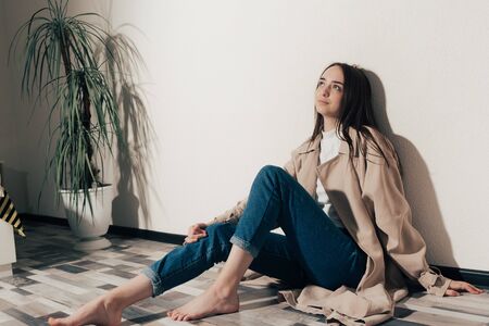 happy girl sitting on the floor looking up and dreaming of another lifeの写真素材
