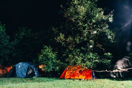 camping at night in the forest . group of tourists sleep in multi colored tent . time for a trip concept .の写真素材