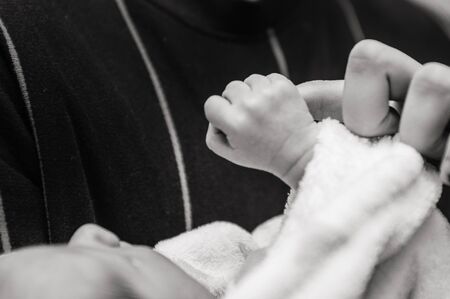 a small newborn baby is holding the finger of its young father . father's love concept . selective...