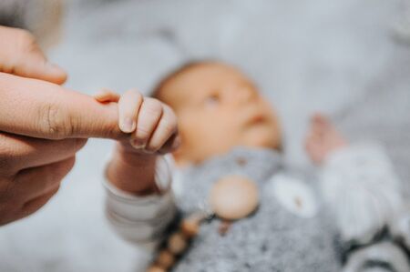 a small newborn baby is holding the finger of its young father . father's love concept . selective focus .の写真素材