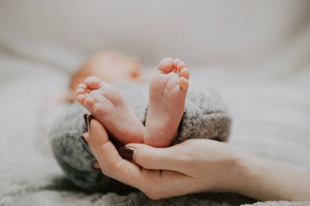 mother holds in her hands the feet of a newborn baby . new life concept .  adopt me please . selective focus .の写真素材
