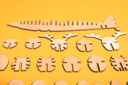 scattered spare parts from a wooden airplane constructor on a yellow background .の写真素材