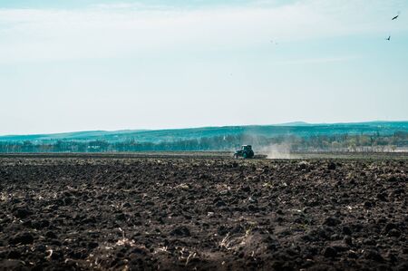 Tractor plows a field in the spring accompanied by rooks tractor . far view . time to plow concept . selective focus .の写真素材