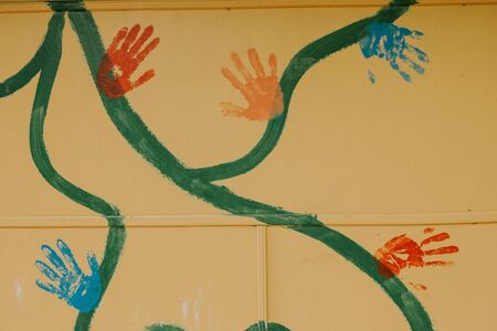 painted wall on which there are large multi-colored prints of children's handsの写真素材