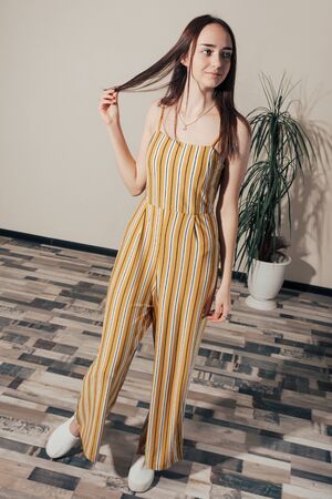 happy girl in yellow woman overalls with white stripes posingの写真素材