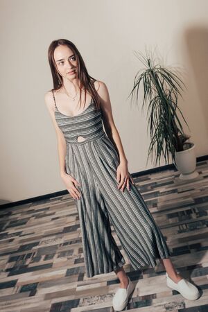 happy girl with blue eyes in grey dress with black stripes posingの写真素材