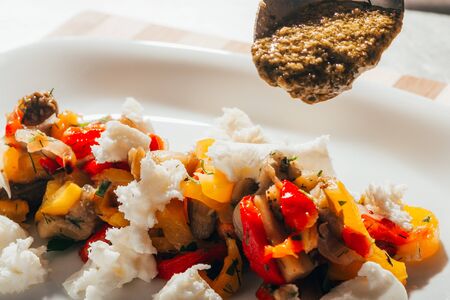 pouring green sauce on rice with vegetablesの写真素材