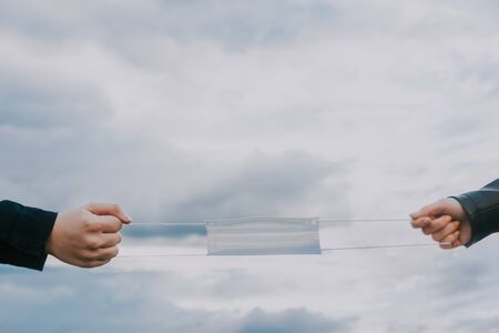 hands holding medical mask with sky background. lack of masks concept