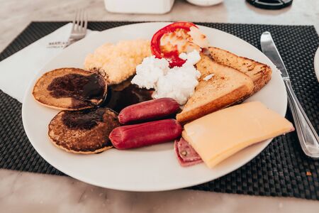 breakfast dish with sausages, cheese bread, omelette and pancakes on the table in the restaurant