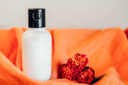 shower gel in travel bottle on orange background with red tropical flowerの写真素材