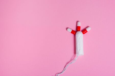 menstruation tampon surrounded by red pills. painkillers for women's critical days .の写真素材