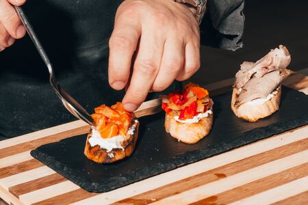 Preparing Italian bruschetta with vegetables and salmon . typical Italian starter in a restaurant and appetizer .の写真素材
