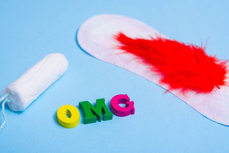 Used feminine sanitary pads and tampon on pink background and word omg . menstruation time concept .の写真素材