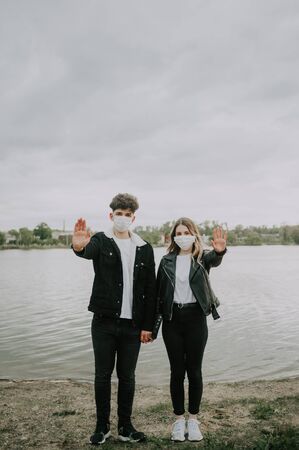 young couple in medical masks show stop sign with hands .の写真素材