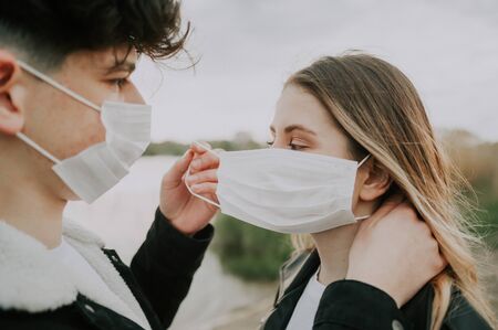 the guy puts on his girlfriend's medical mask . caring guy concept .の写真素材