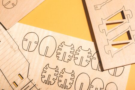 scattered spare parts from a wooden airplane constructor on a yellow background .