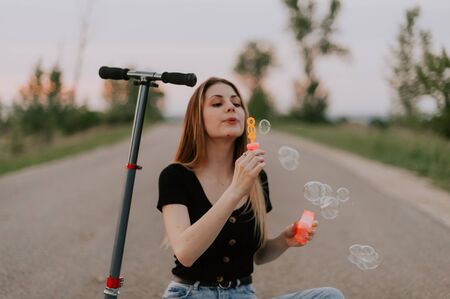 woman blows soap bubbles on the scooterの写真素材