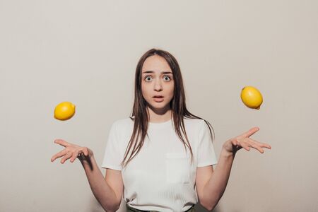 girl cannot make a choice between two lemons. uncertain girl concept. woman logicの写真素材