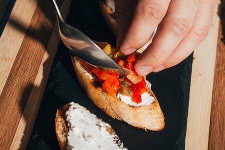 Preparing Italian bruschetta with vegetables and salmon . typical Italian antipasti starter in a...