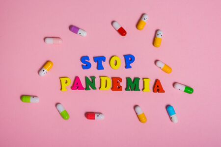 word STOP PANDEMIA made of wood letters.  multi colored tablets around the word   .の写真素材