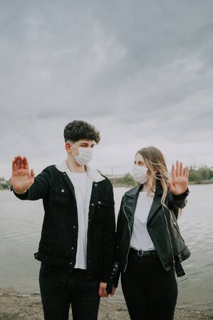 young couple in medical masks show stop sign with hands .の写真素材