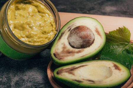 spoiled avocado and jar of guacamole on a wooden pallet . product recycling concept .の写真素材