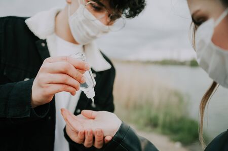 guy disinfects his girlfriend hands with antiseptic . quarantine care concept. close up .の写真素材