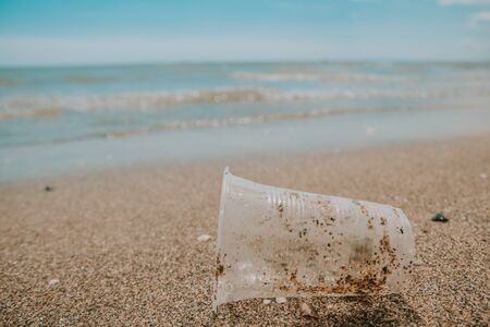 Rubbish plastic disposable cup on sandy beach around the sea. plastic waste pollutionの写真素材