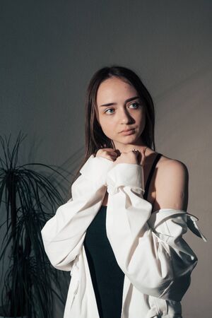 portrait of girl in a black dress and white coat posing .の写真素材