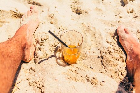 orange refreshing cocktail at the beach on sandの写真素材