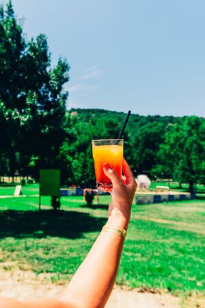 orange refreshing cocktail near the hotel on green backgroundの写真素材