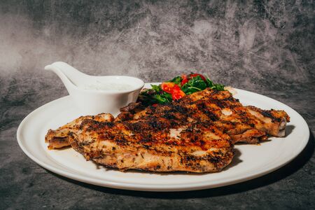 Grilled pork chop steak with fresh vegetable salad and sauce on plate  .の写真素材