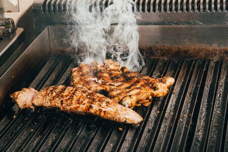fried meat on  grill . cooking tasty steaks with smoke   .の写真素材