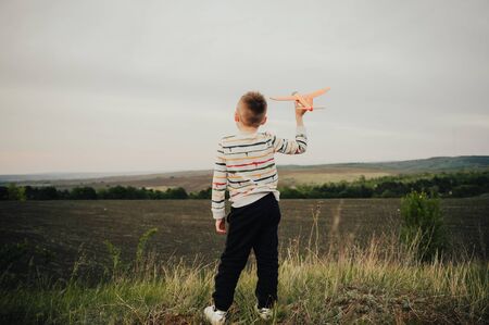 boy playing with orange toy plane outside in the fieldの写真素材