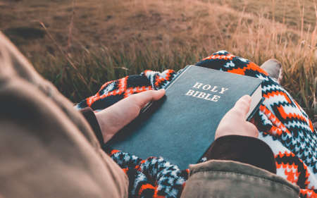 girl is looking at the holy bible at sunrise  on hill .の写真素材