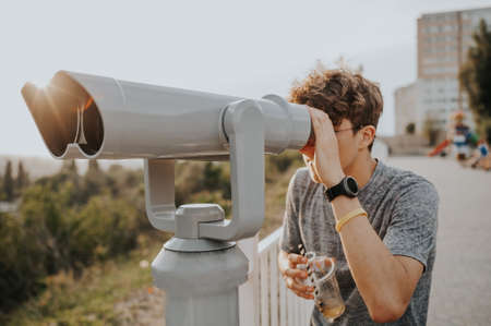 man with cocktail watch in telescope with city skylineの写真素材