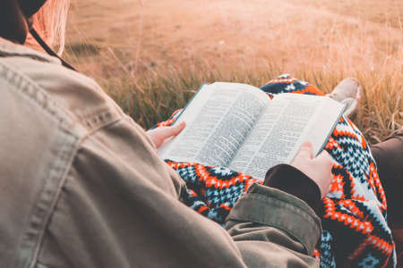 girl reads the bible at sunrise  on hill .の写真素材