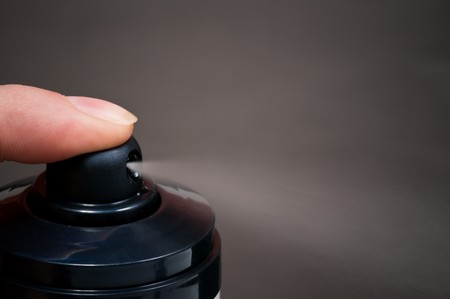 Close-up of black aerosol can showing off the spray against gray backgroundの写真素材