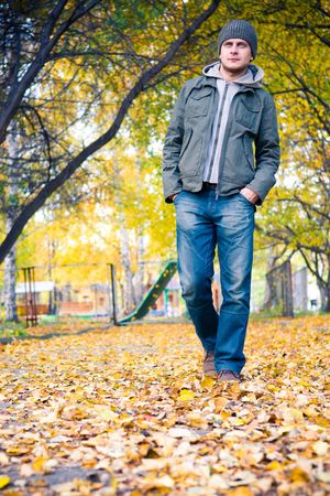 Young man walking in the autumn parkの写真素材