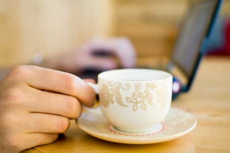  Hand with cup of coffee. Working on computer. 