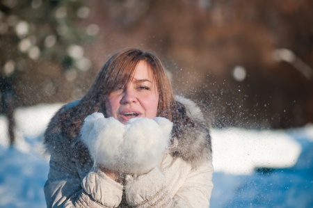 Beautiful woman blowing in the snow の写真素材