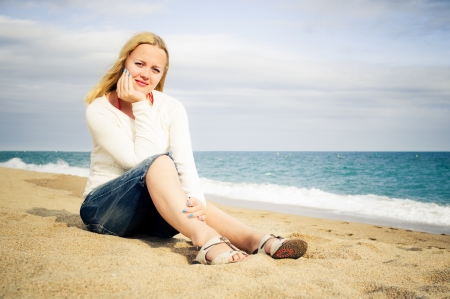 woman sit on the beach by the sea wearing jeansの写真素材
