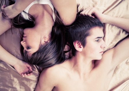Upset couple sleeping separately on their bed の写真素材