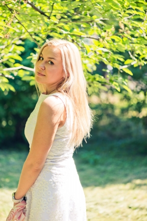 Beautiful young blond woman in a white dress outdoors の写真素材