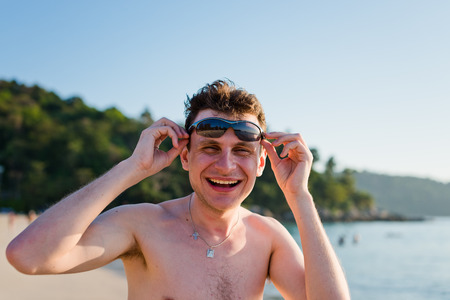 Handsome young man smiling on the beach. の写真素材