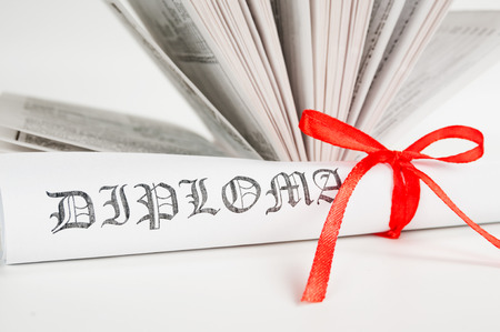 Diploma with red ribbon and open book の写真素材