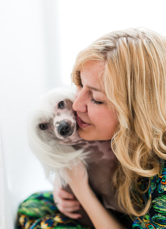 Woman keeping Chinese crested dog near her face 