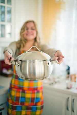 young woman with sauce pan indoor の写真素材