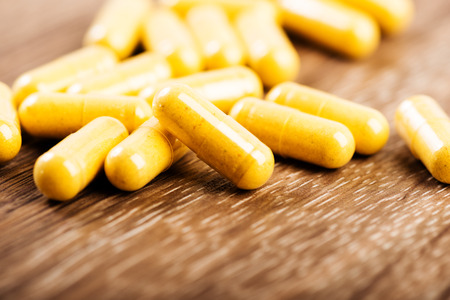 Pills spilling out on old wooden tableの写真素材