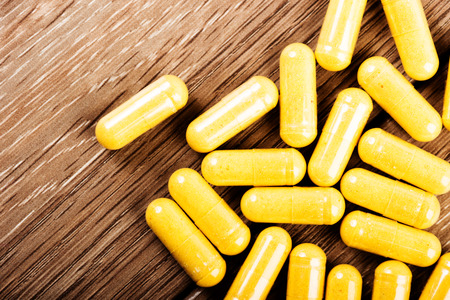 Pills spilling out on old wooden tableの写真素材